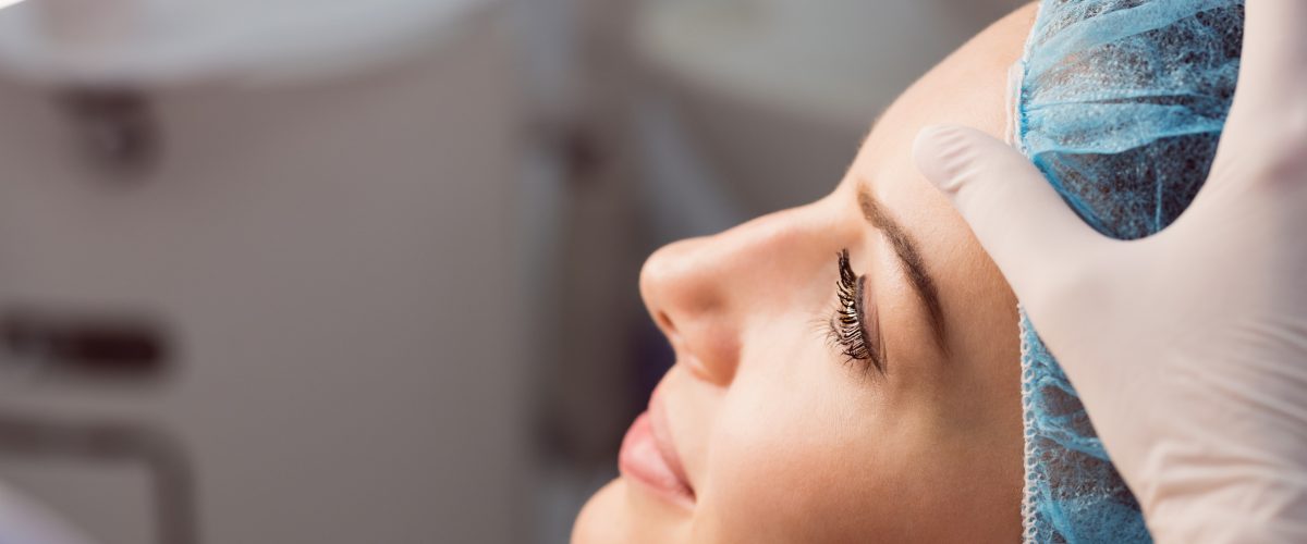 Hands of doctor examining womans face for cosmetic treatment at clinic